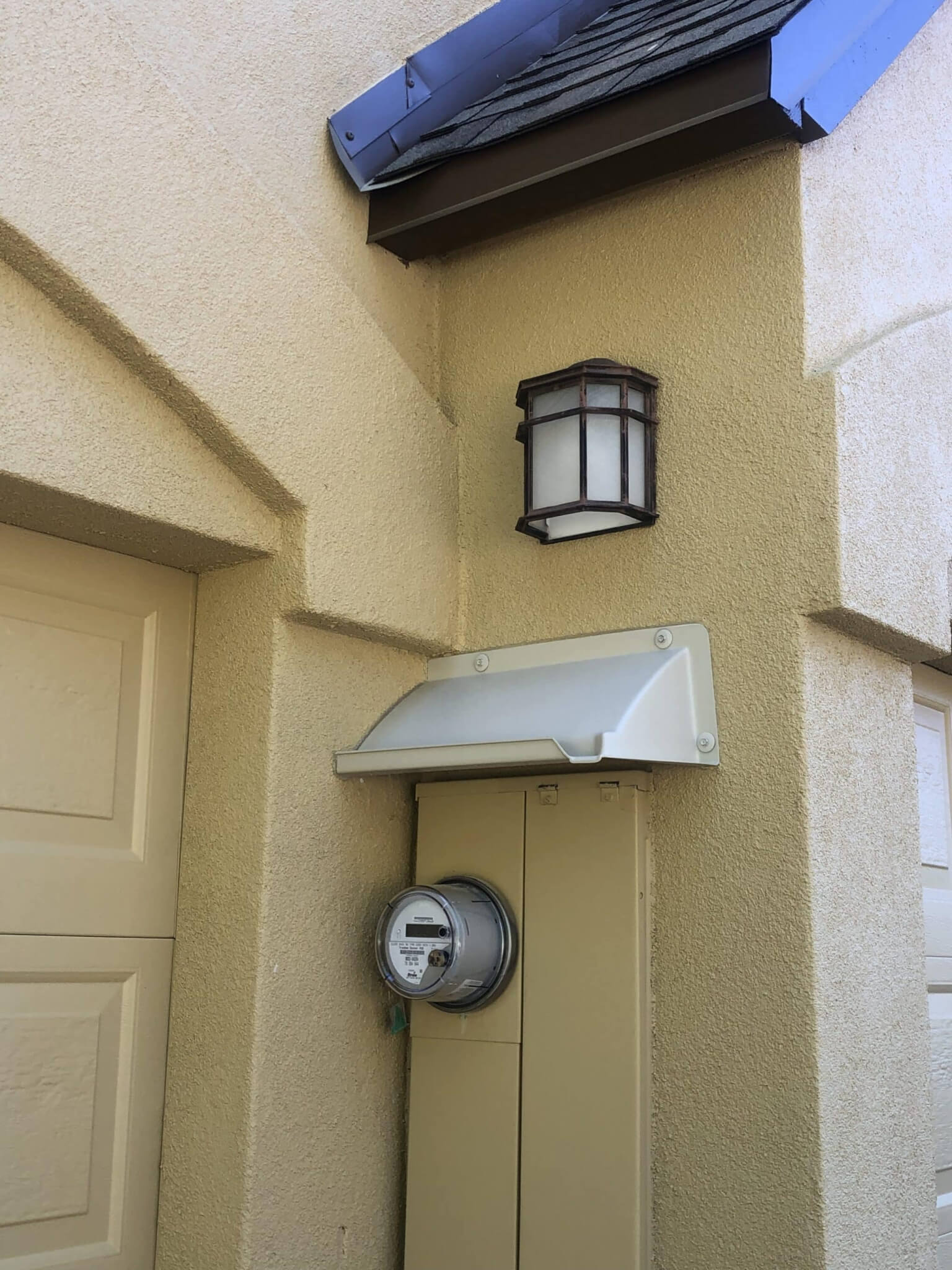 Off white door canopy mounted over a mustard color electric service panel.