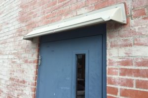 A picture of an 8 inch high by 8 inch projection canopy made of ABS plastic above an exterior door to divert rain.
