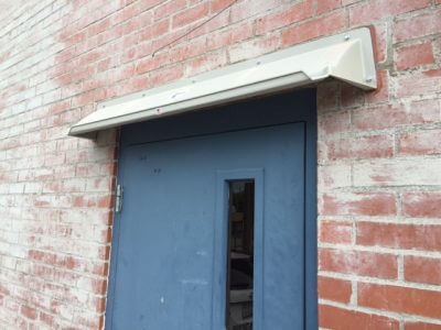 A picture of an 8 inch high by 8 inch projection canopy made of ABS plastic above an exterior door to divert rain.