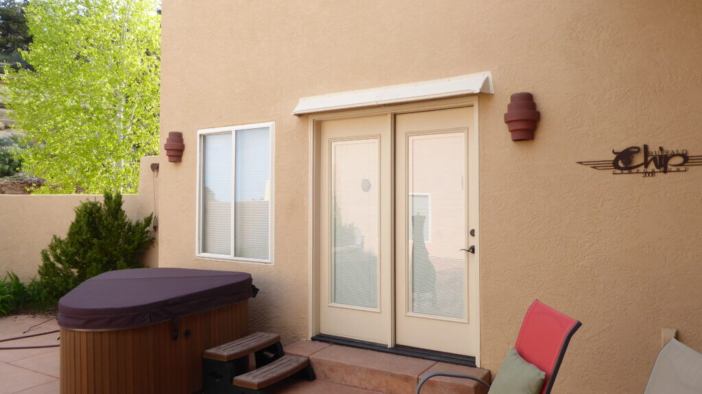 Image of a DOORBRIM rain diverter mounted above 2 full glass panel French doors.