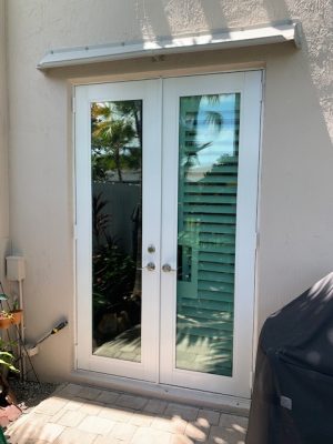 Image of a DOORBRIM rain diverter mounted above 2 full glass panel French doors.