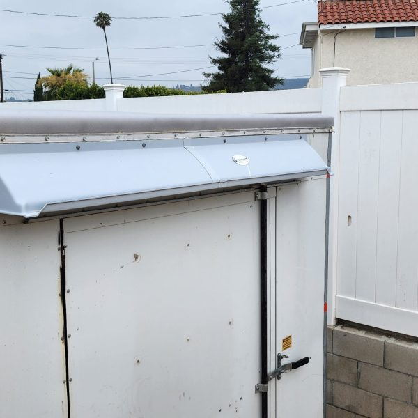 Gray DOORBRIM rain diverter mounted above a walk-in refrgeration box.