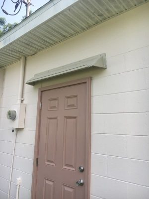 Beige doorbrim rain diverter over a brown exterior 6 panel door.