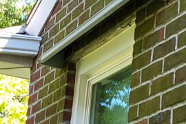 Doorbrim rain diverters mounted above a window in a red brick building.
