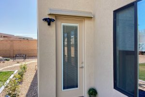 Beige DOORBRIM rain diverter mounted above a brown patio entrance door with a full glass insert.