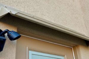 Beige DOORBRIM rain diverter mounted above a brown patio entrance door with a full glass insert.