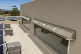 Beige DOORBRIM rain diverter installed over two wide clerestory windows.