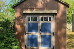 Beige rain guard for shed mounted above double blue and beige doors.