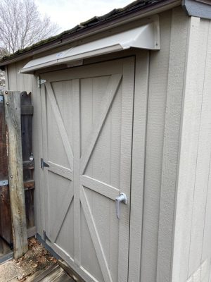 DOORBRIM rain guard mounted above double shed doors.