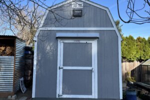 Gray DOORBRIM awning mounted above Doors on a gray shed with white trim.