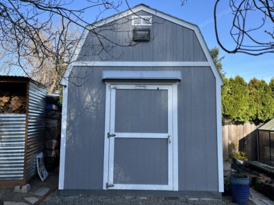 Gray DOORBRIM awning mounted above Doors on a gray shed with white trim.